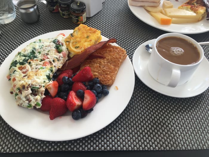 Breakfast of mixed berries, hashbrowns, egg white omelette, bacon and coffee