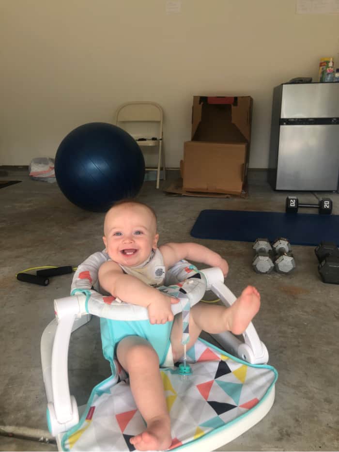 Jacob smiling sitting in his sit-me-up chair in the garage during a workout