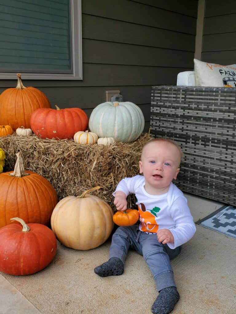 Jacob sitting on the patio next to the pumpkins