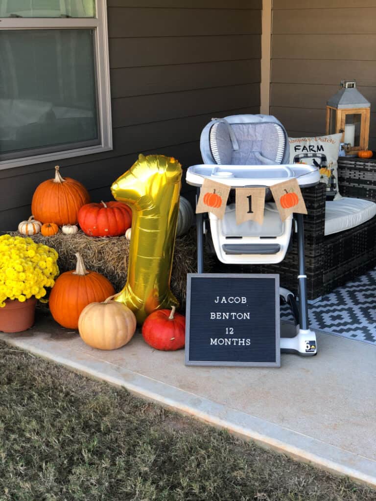 Outdoor party decorations... pumpkins on a hay stack, a birthday board, and the high chair with a pumpkin banner