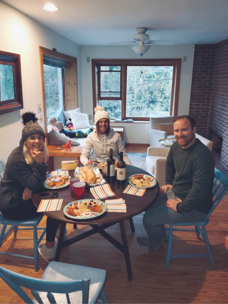 Lindsey, Megan, and Jamey sitting down at the table for dinner.