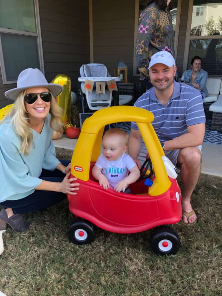 Lindsey and Joey next to Jacob as he rides in his car in the backyard.