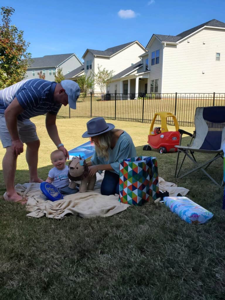 Joey and Lindsey opening gifts with Jacob. He is smiling with his new stuffed animal lion.