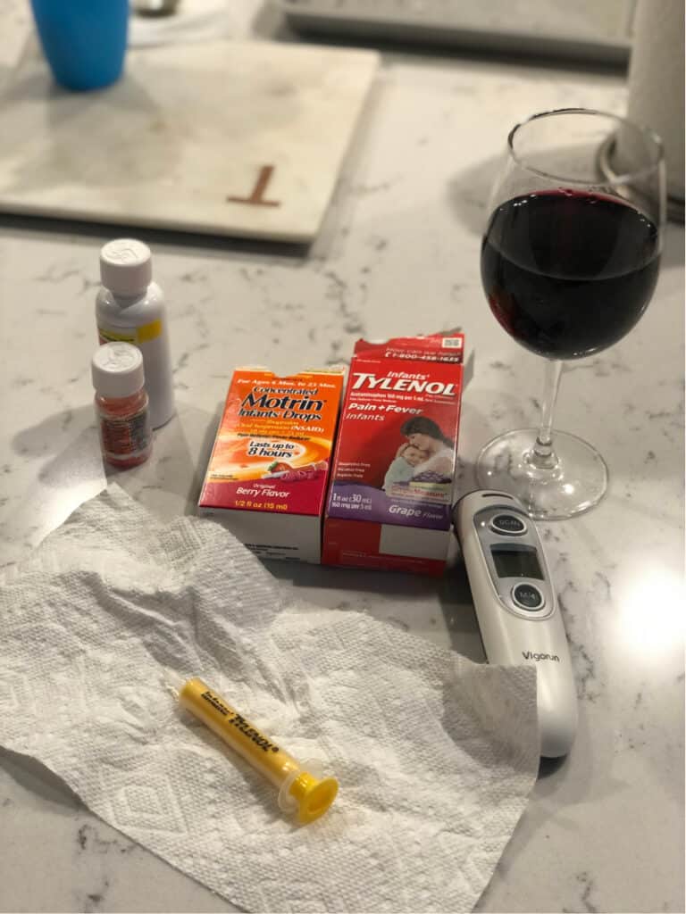 Infant tylenol, infant motrin, thermometer and a glass of wine on the counter