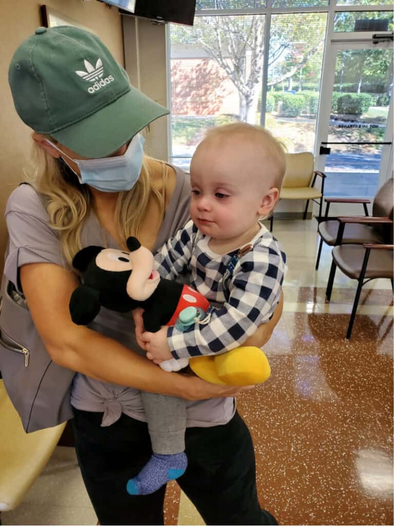 Lindsey holding Jacob at Urgent Care as he snuggles Mickey Mouse.