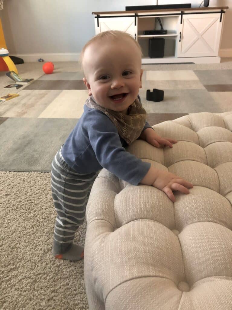 Jacob standing with his hands on the ottoman. 