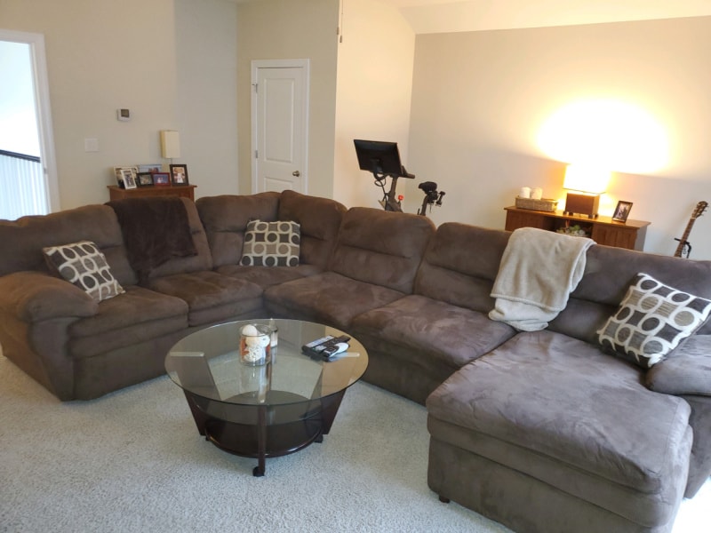 The large, brown couch and glass coffee table in the mancave.