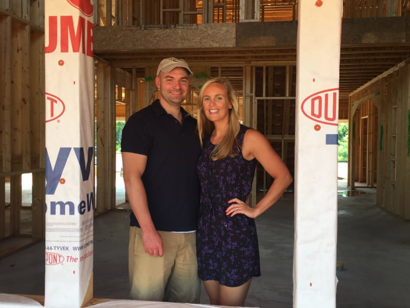 Joey and Lindsey standing in a window of their house in the building stages