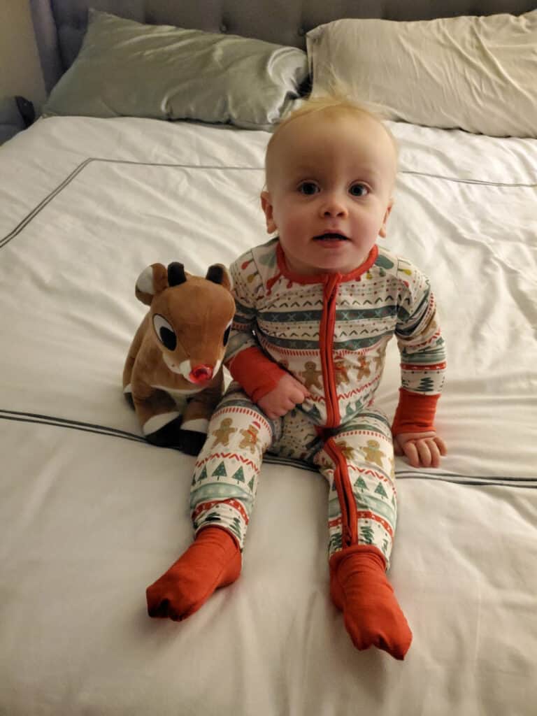 Jacob sitting on the bed in his Christmas pjs with Rudolph