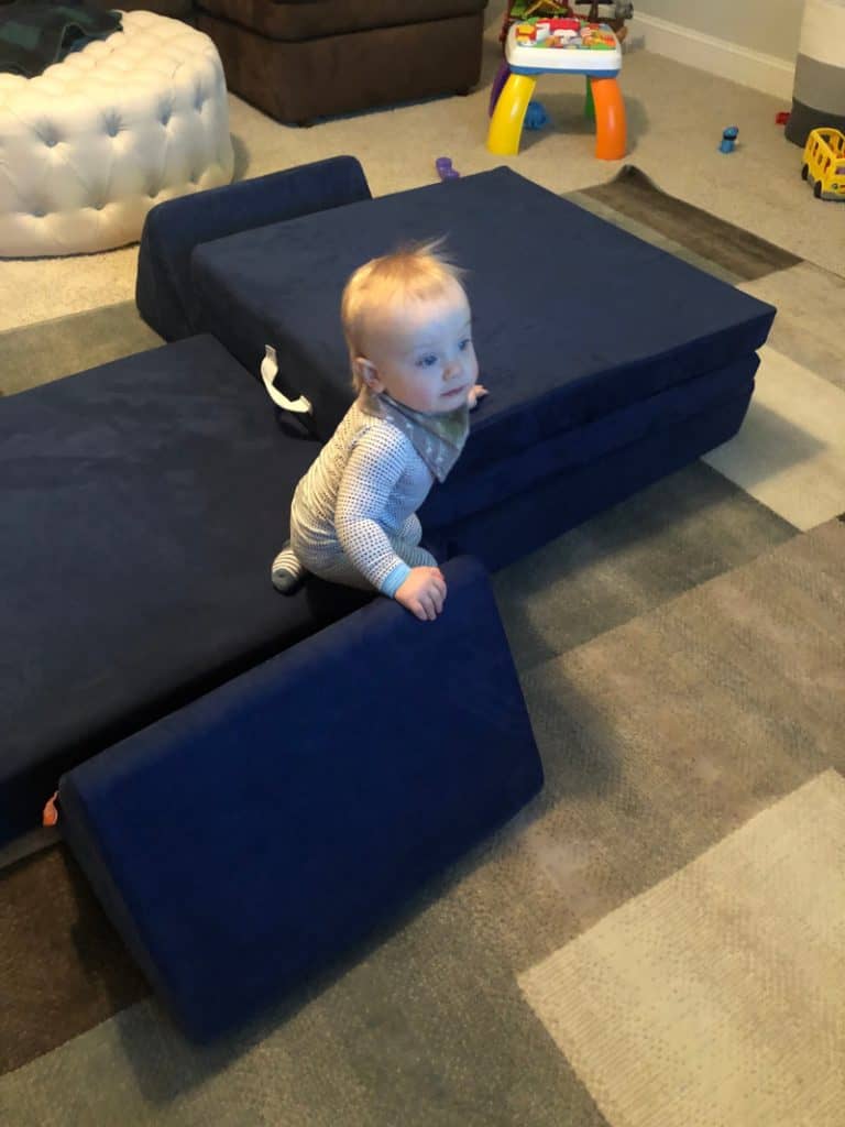 Jacob climbing on the blue nugget couch in the playroom.