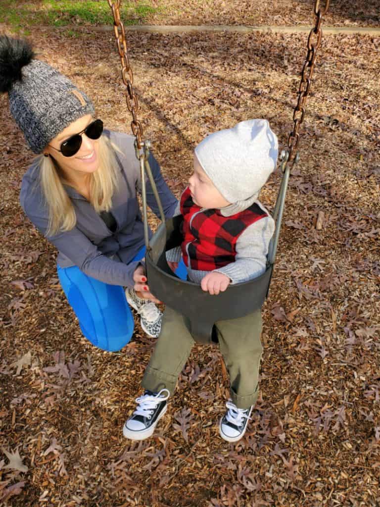 Jacob swinging at the park and Lindsey smiling next to him