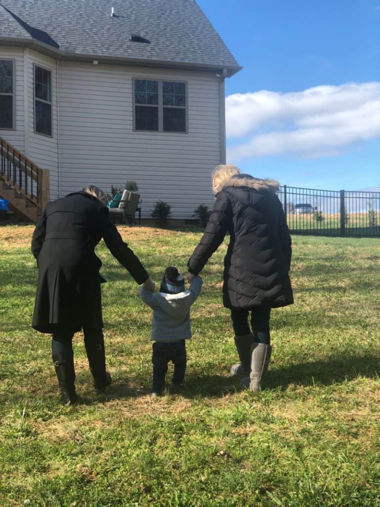 Jacob walking up a hill holding Grammy and Mommy's hands