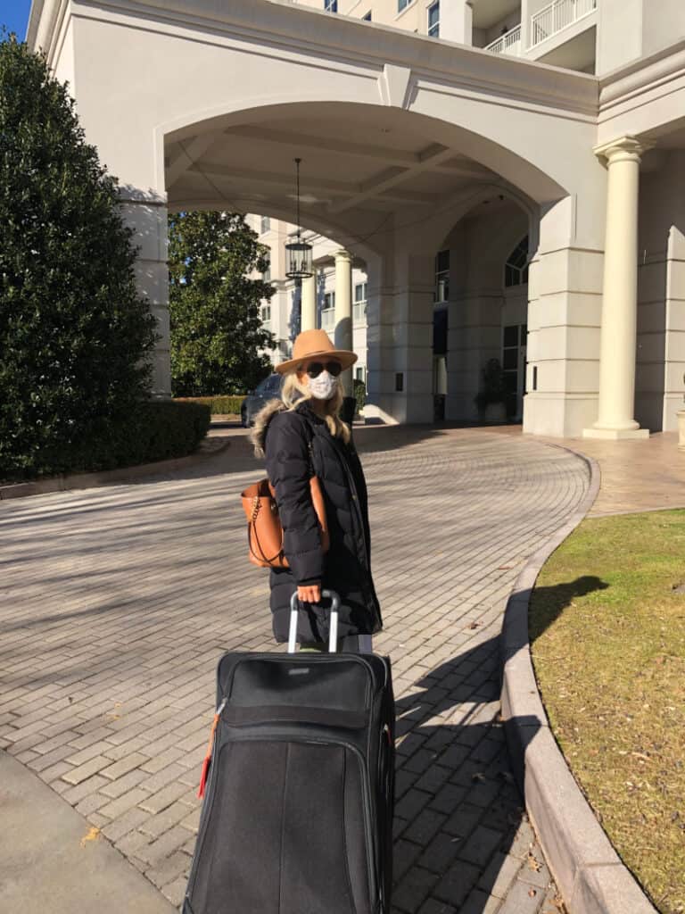 Lindsey with a giant luggage bag in front of the hotel